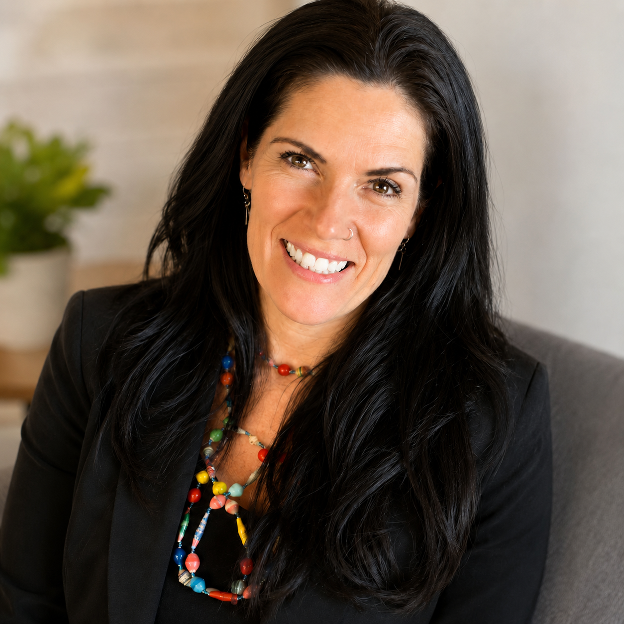 Judi Hampshire, Online Business Manager and Digital OBM, smiling in a black blazer with a colourful beaded necklace.